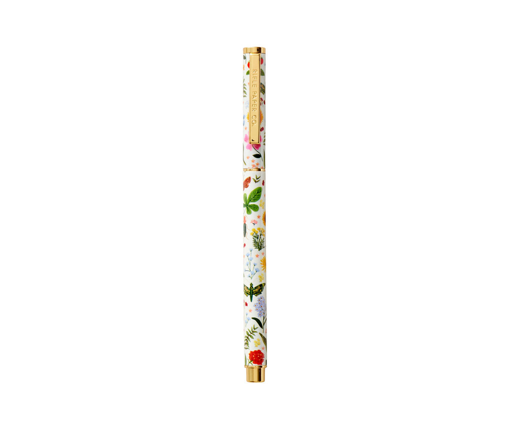 The Curio Pen, a slender white rollerball with colorful floral designs and gold accents on the cap and tip, features 0.5mm gel ink and is shown against a plain white background.
