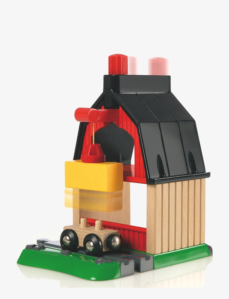 The BRIO World Train Set Farm Railway Set features a wooden barn with a black roof, red inside, green base, and a yellow hay bale lifted by a red crane onto the magnetic train car.