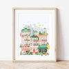 The Paint By Number Kit - New York features a vibrant cityscape with colorful buildings, a bakery, fire escapes, potted plants, a yellow taxi, and skyscrapers—perfectly displayed against a white wall on a wooden floor.