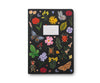The Assorted Set of 3 Curio Notebooks features black stitched covers with vibrant illustrations of flowers, leaves, butterflies, beetles, and a ladybug. Each has a beige center label reading "Notebook." Ideal for ruled notebook enthusiasts.