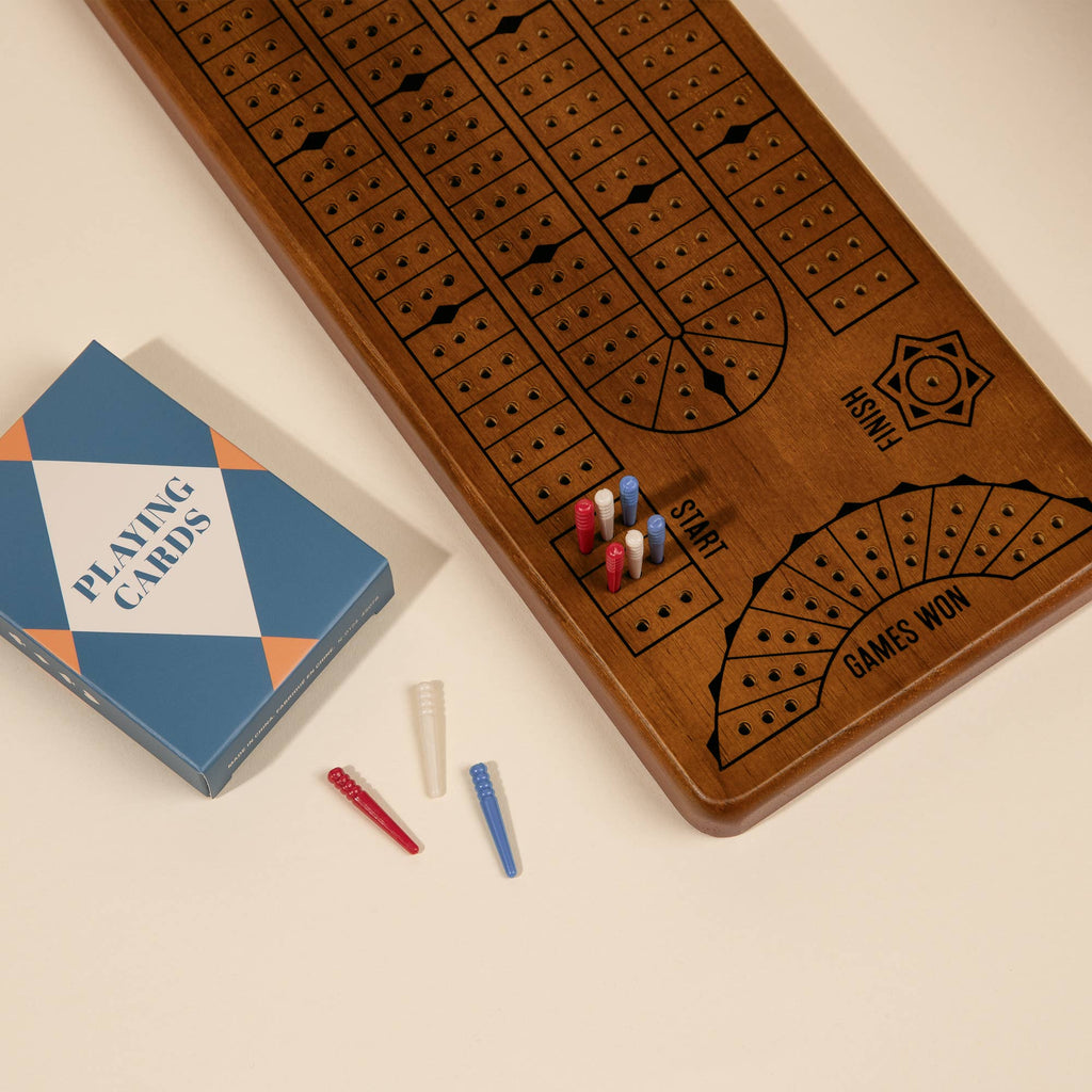 The 3-in-1 Game Collection: Scrabble, Trivial Pursuit & Cribbage includes a wooden cribbage board with red, white, and blue pegs plus cards—ideal for fans seeking a classic game night experience.