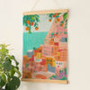The Diamond Painting Kit - Positano by Petra Lidze features a vibrant coastal hillside town with pastel buildings, lush greenery, orange trees, a turquoise sea, and a potted plant in the foreground.
