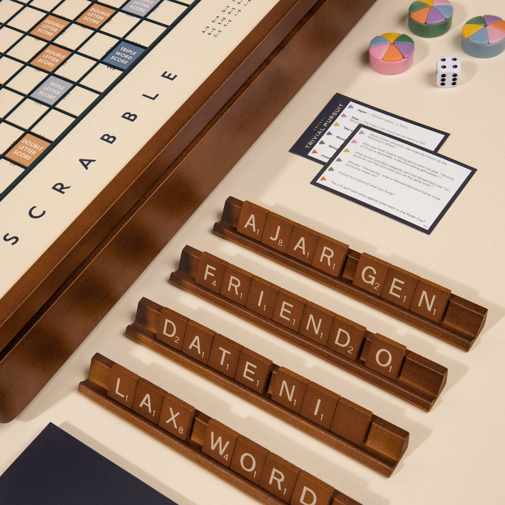 The 3-in-1 Game Collection features a Scrabble board with four tile racks (“ARGEN,” “FRIENDO,” “DATENI,” “LAX WORD”) plus Trivial Pursuit cards, dice, and pie tokens for extra fun at the table.