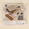The image shows the back of the 3-in-1 Game Collection: Scrabble, Trivial Pursuit & Cribbage box with game boards, pieces, Scrabble tiles, racks, cards, and a storage bag displayed.