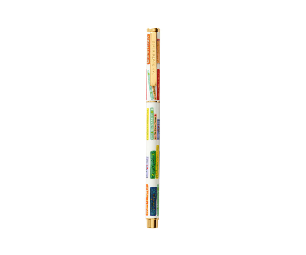 The Book Club Pen is a white rollerball with gold accents, adorned with colorful vertical labels of place names and illustrated scenes. It stands upright against a white background and is compatible with gel ink refills for smooth writing.