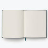The Strawberry Fields Embroidered Sketchbook, featuring blank white pages and a blue ribbon bookmark, is open on a plain light background.