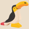 The Holztiger Toucan is a handcrafted wooden toy made from maple and beech, painted in black, white, yellow, and orange with a bold yellow-orange beak and red tail. Ships in one week. Part of the HOLZTIGER figures collection.