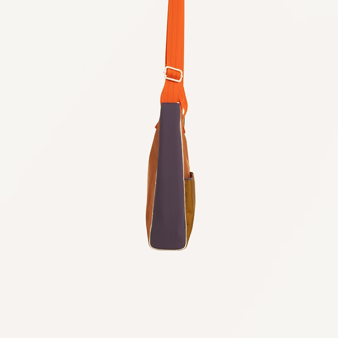 A side view of the Sticky Lemon Shoulder Bag | Leather Ball + Golden Cup, featuring an orange strap, brown body, dark purple panel, and crafted from recycled PET bags, set against a plain off-white background.