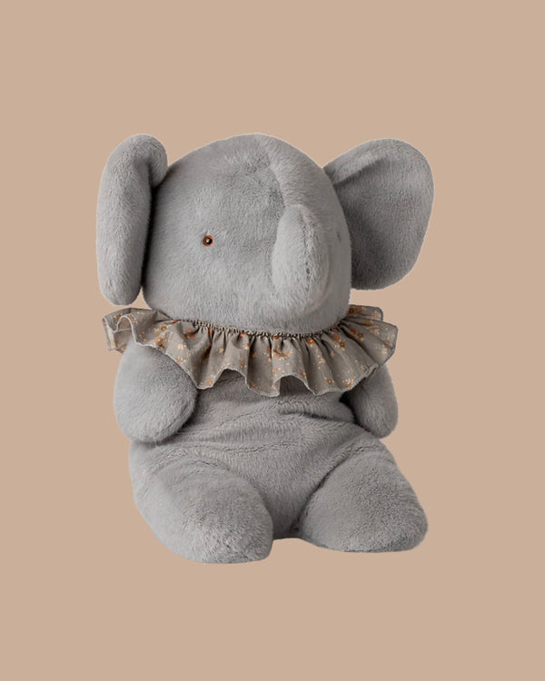 The PRE-ORDER: Elephant Plush, Big - Blue/Grey (ships late November) is crafted from the softest plush and recycled polyester, featuring large ears, a brown eye, and a floral ruffled collar against a plain beige background.