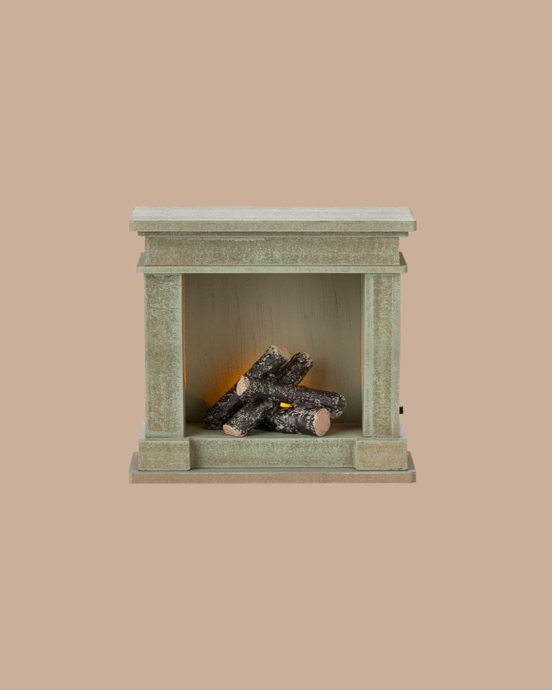 PRE-ORDER: Fireplace, Miniature – Dusty Green (ships early October), features a small rectangular shape with vintage finish and artificial logs; perfect for adding charm to any miniature home. Set against a plain beige background.