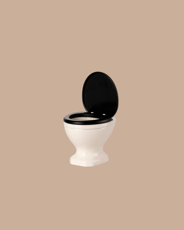 An off white mouse-sized toilet with a black seat and lid is shown open, centered on a plain light brown background—perfect for SuitCasa mouse houses. PRE-ORDER: Toilet, Mouse Size - Off White (ships early November).