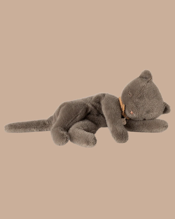 The PRE-ORDER: Sleeping Kitten Plush, Medium - Grey features closed eyes and a brown collar, lying on its side in a relaxed pose against a beige background. Made from soft recycled polyester. Estimated Ship Date: Late November.