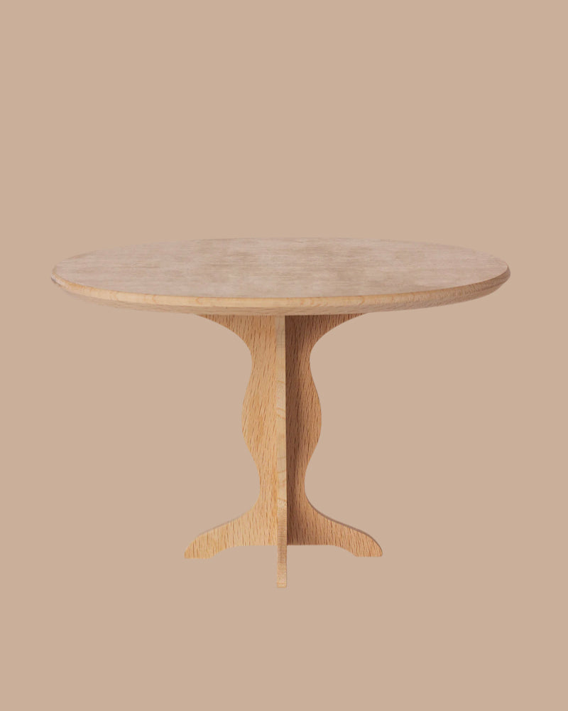 The PRE-ORDER: Oval Table, Mini - Nature (ships early October) features a light wood finish, fine craftsmanship, and a sculpted central pedestal base, presented against a plain beige background.