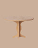 The PRE-ORDER: Oval Table, Mini - Nature (ships early October) features a light wood finish, fine craftsmanship, and a sculpted central pedestal base, presented against a plain beige background.