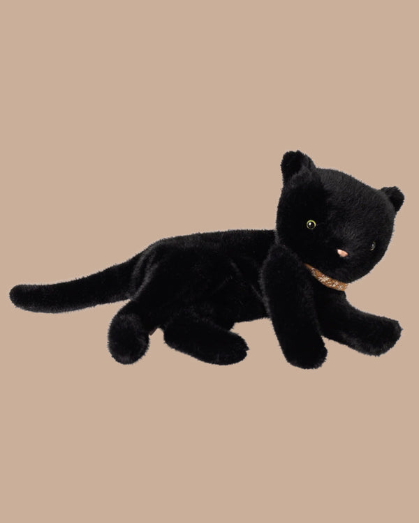 The PRE-ORDER Sleeping Kitten Plush, Medium - Black, features a soft plush cat with green eyes and a pink nose, lying on its side in a cosy basket with a sparkly collar; ships late November.