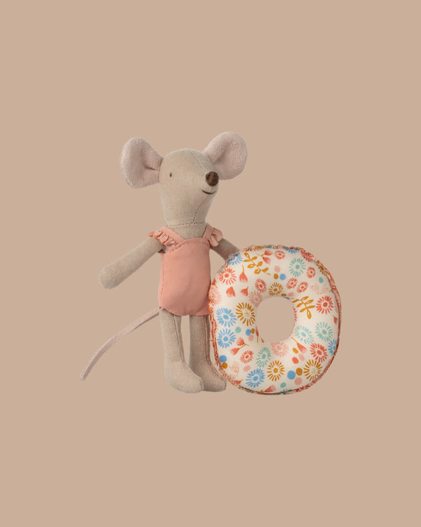 The Maileg Beach Mouse With Float, Little Sister - Flower features a small fabric mouse in a pink swimsuit holding a floral-patterned float, posed against a plain beige background.