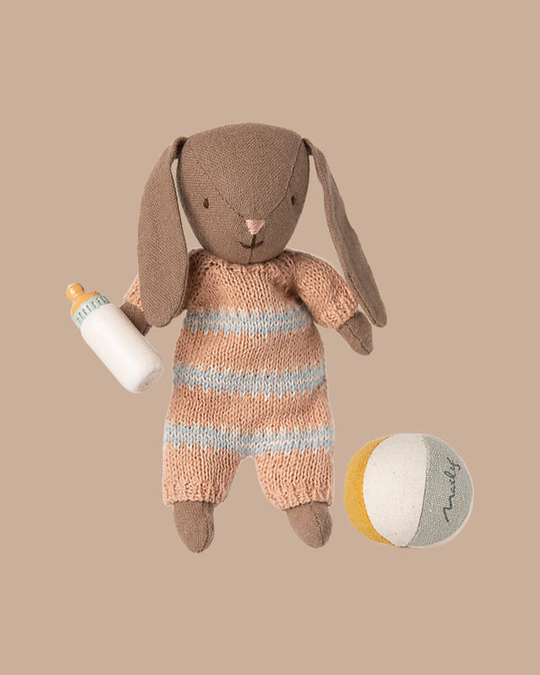 The PRE-ORDER: Bunny Set, Micro - Brown - Dusty Rose (ships early November) features a brown bunny in a striped knit romper holding a baby bottle, with a soft yellow, white, and gray ball nearby on a beige background.