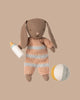 The PRE-ORDER: Bunny Set, Micro - Brown - Dusty Rose (ships early November) features a brown bunny in a striped knit romper holding a baby bottle, with a soft yellow, white, and gray ball nearby on a beige background.