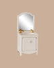 The PRE-ORDER: Sink Dresser, Mouse - Off White (ships early September) features a small white vanity with a cabinet, gold faucets, and an arched mirror styled with bathroom essentials against a beige background.