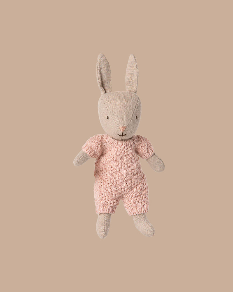 The PRE-ORDER Rabbit Micro - Sand in a rose knitted suit (ships early October) sits upright on a plain beige background—ideal for House of Miniature dollhouse displays or pairing with Maileg accessories.