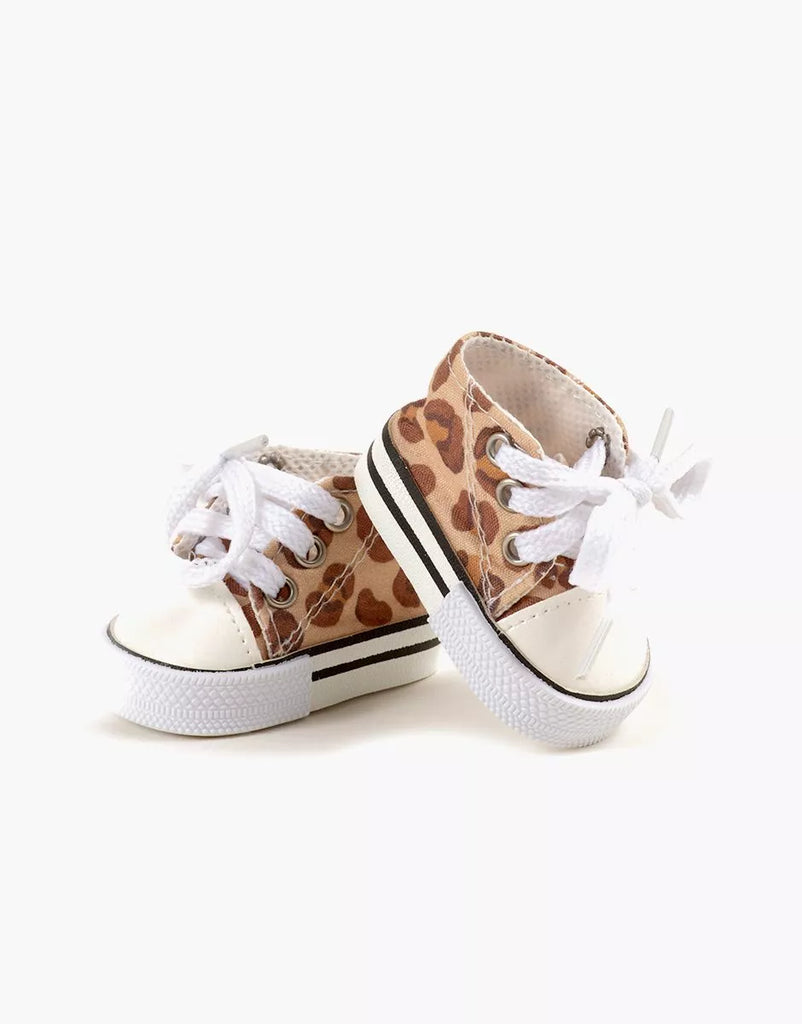 Minikane Doll Shoes | Converse Style Feline Print Sneakers: two small lace-up shoes with white soles, white laces, and a brown leopard print fabric. The sneakers are positioned with one leaning against the other on a plain white background.