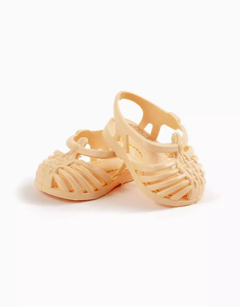 A pair of small peach Minikane Beach Sandals with woven straps and ankle closures for dolls, shown against a plain white background.