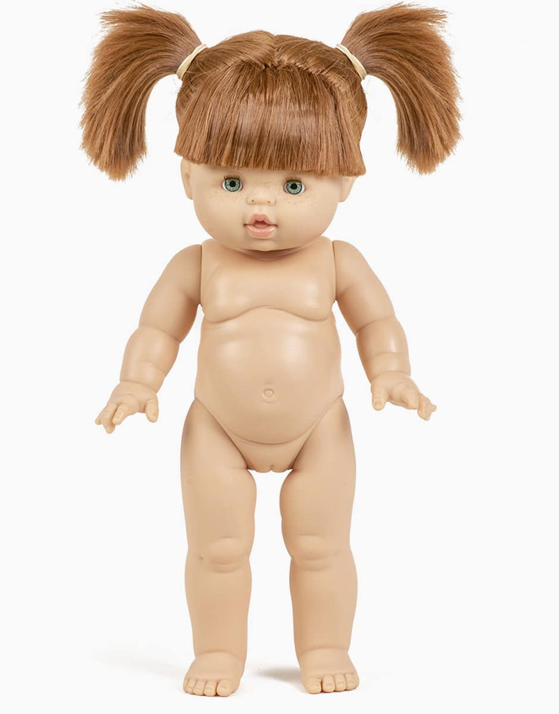 The Minikane Standing Doll (14") - Gabriella is an anatomically correct, nude doll with light skin, green eyes, and brown hair in two high pigtails. Made in Spain, she stands upright against a white background. Clothing sold separately.