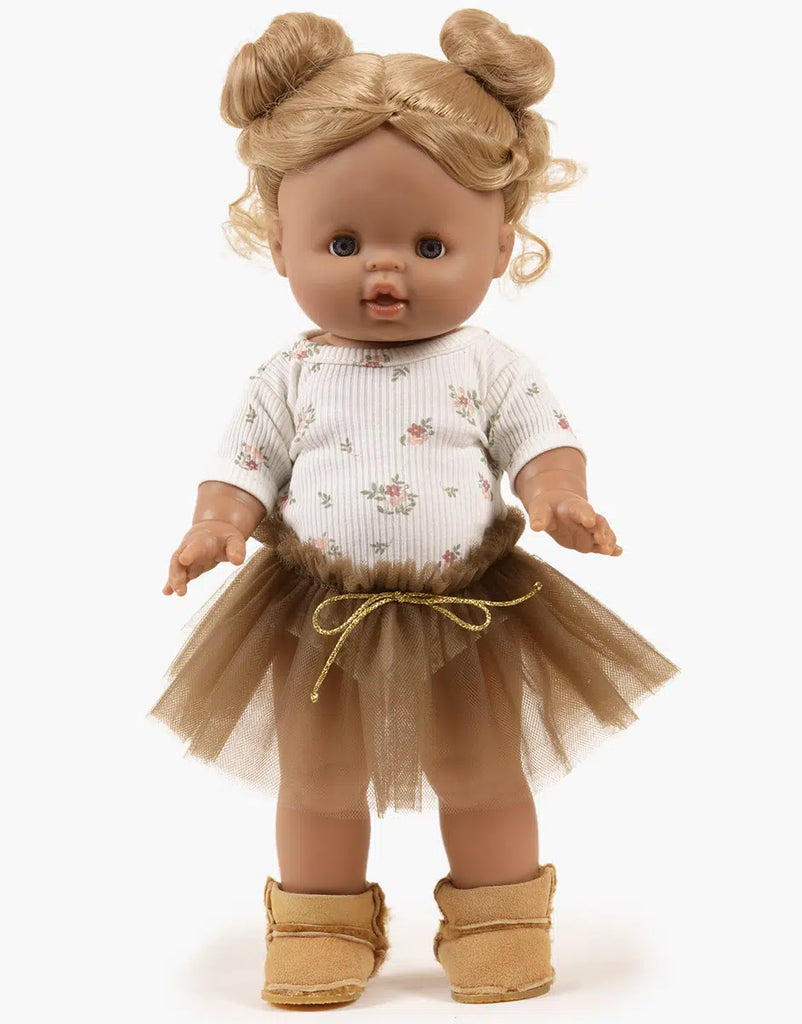 A brown-skinned Minikane doll with light brown hair in two buns, wearing the Josepha Set: a pink flower bodysuit and brown tutu. The doll stands upright in tan boots against a plain white background. Outfit is hand washable.