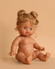 The Minikane Baby Doll (13") - Louise features light brown skin, blue eyes, and curly blonde hair in two buns. This anatomically correct doll sits upright against a beige background. Clothing sold separately—perfect for realistic play.