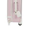 Close-up of the Olli Ella See-Ya Suitcase - Pink, showing its pink body with white trim, a white retractable handle, a white luggage tag, visible wheel, and zipper.