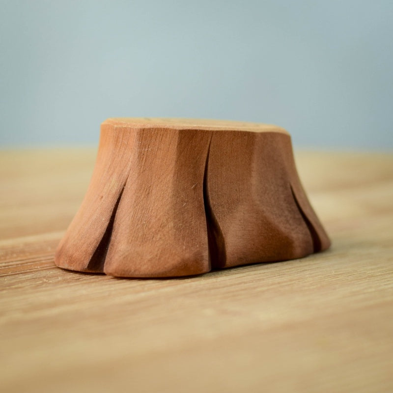 The Bumbu Handmade Wooden Tree Stump and Lovebirds Set, with a smooth finish and bark-like grooves, rests on a light wooden surface.