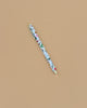 The Curio Pen, a 0.5mm gel ink rollerball with a floral design in red, green, and blue accents, rests diagonally on a plain light brown surface.