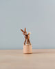 A Wobbly Rabbit Push Toy with articulated limbs and a fluffy tail, handmade in Germany, standing on a small wooden spool against a light gray background.