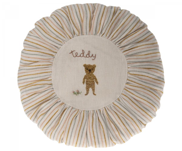 A round Maileg Cushion, Small with a central embroidered design featuring a teddy bear and the word "teddy", surrounded by striped beige and white pleated edging.
