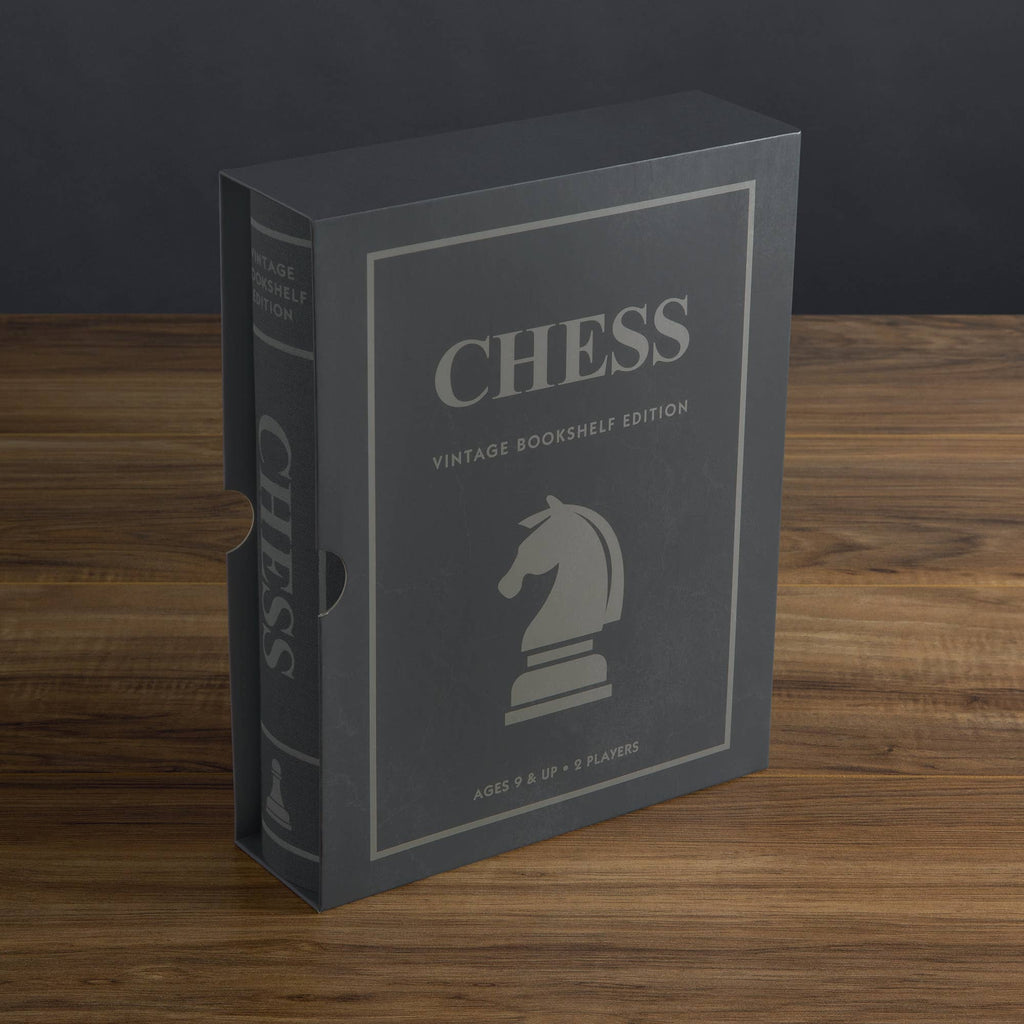 A gray box labeled "Chess Vintage Bookshelf Edition" with a knight chess piece graphic sits upright on wood. This collectible strategy game is for ages 9+ and supports up to 8 players.