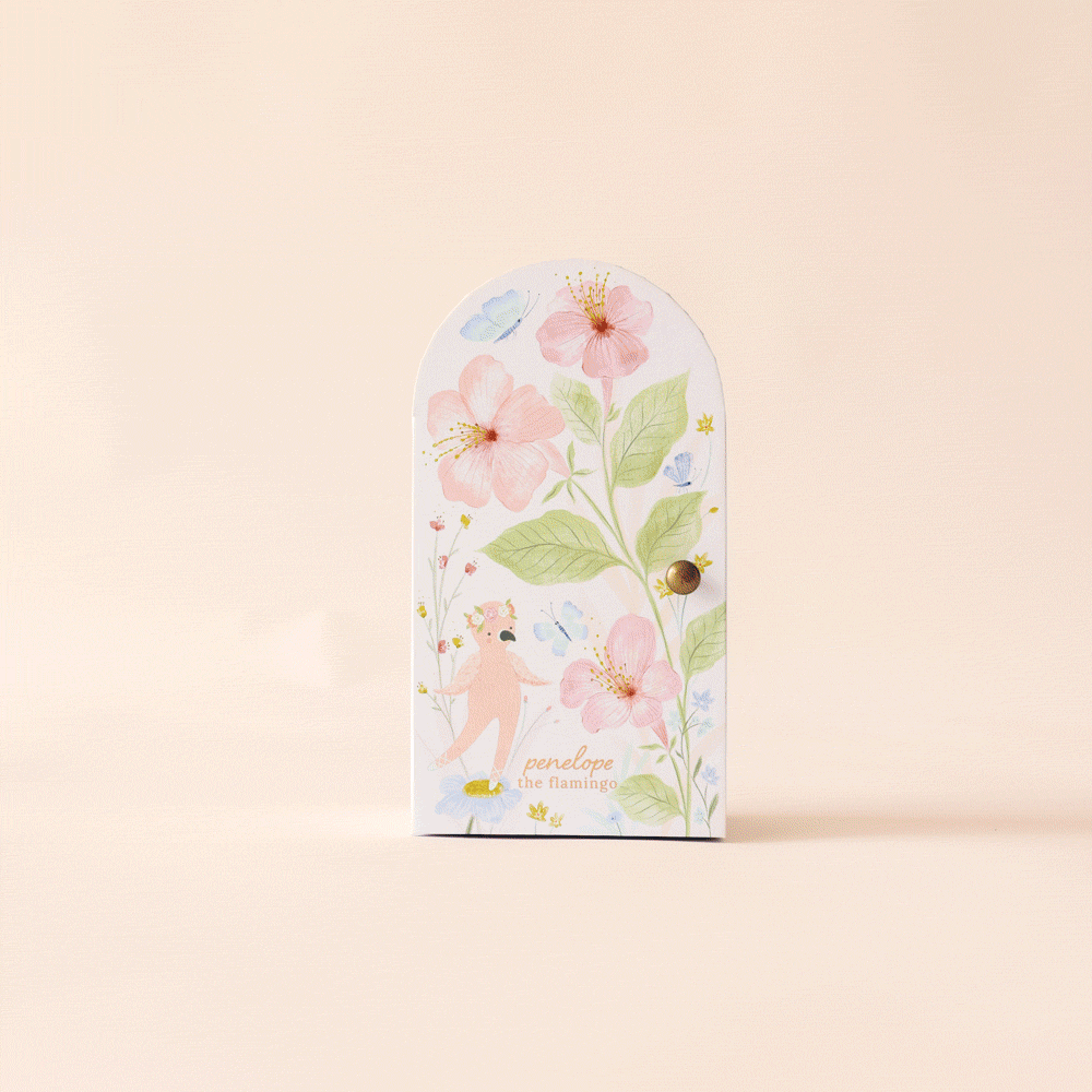 A handmade Peruvian card features an illustrated flamingo, pink flowers, and green leaves on a soft peach background. It’s designed with an arched window style and a golden knob on the right.