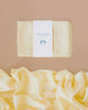 Folded and loose yellow Sarah's Silk Giant Lambswool Playsilk set against a beige background. Crafted from pure mulberry silk, the folded piece has a label that reads "Giant Playsilk." The fabric's smooth and soft texture enhances its Winter colorways appeal.