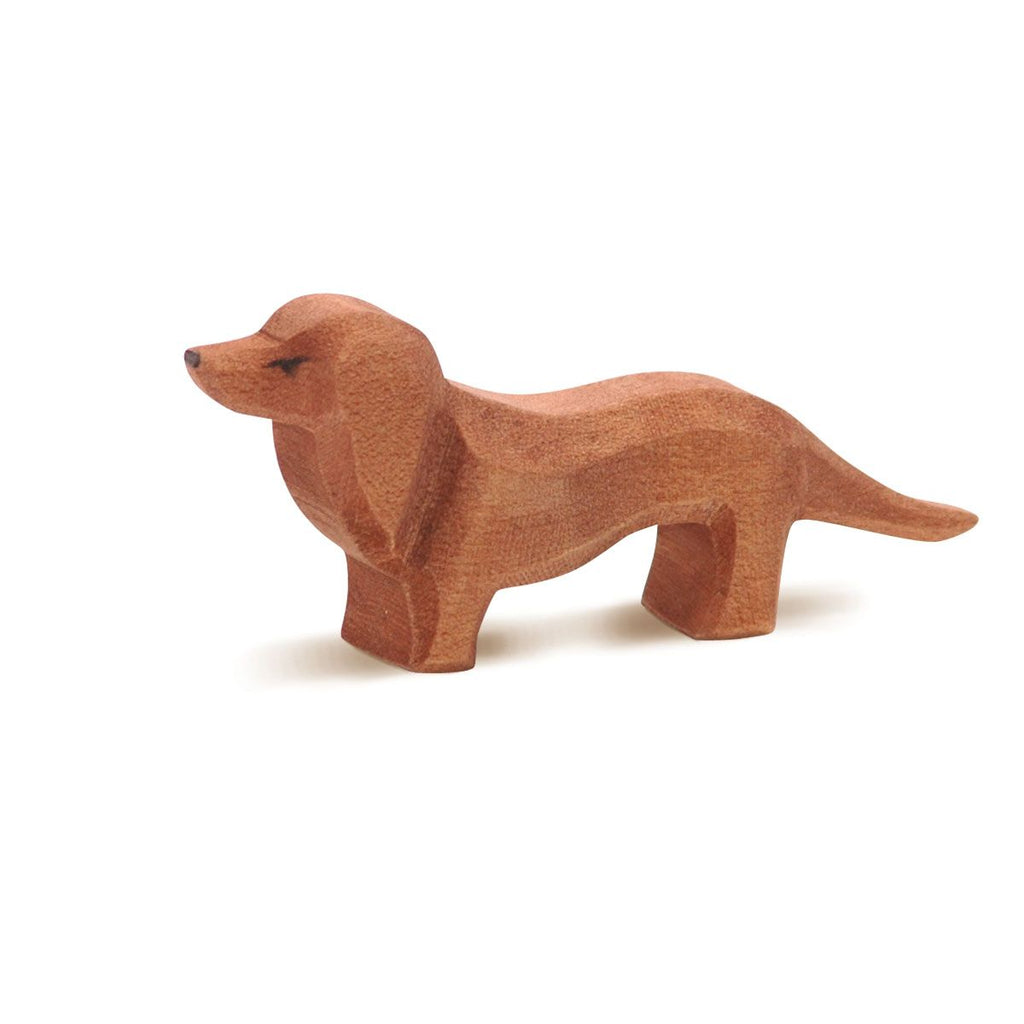 The Ostheimer Dachshund Dog is a simple, hand-carved wooden figurine with a smooth finish, inspired by classic handcrafted toys—perfect for imaginative play. Shown on a white background.
