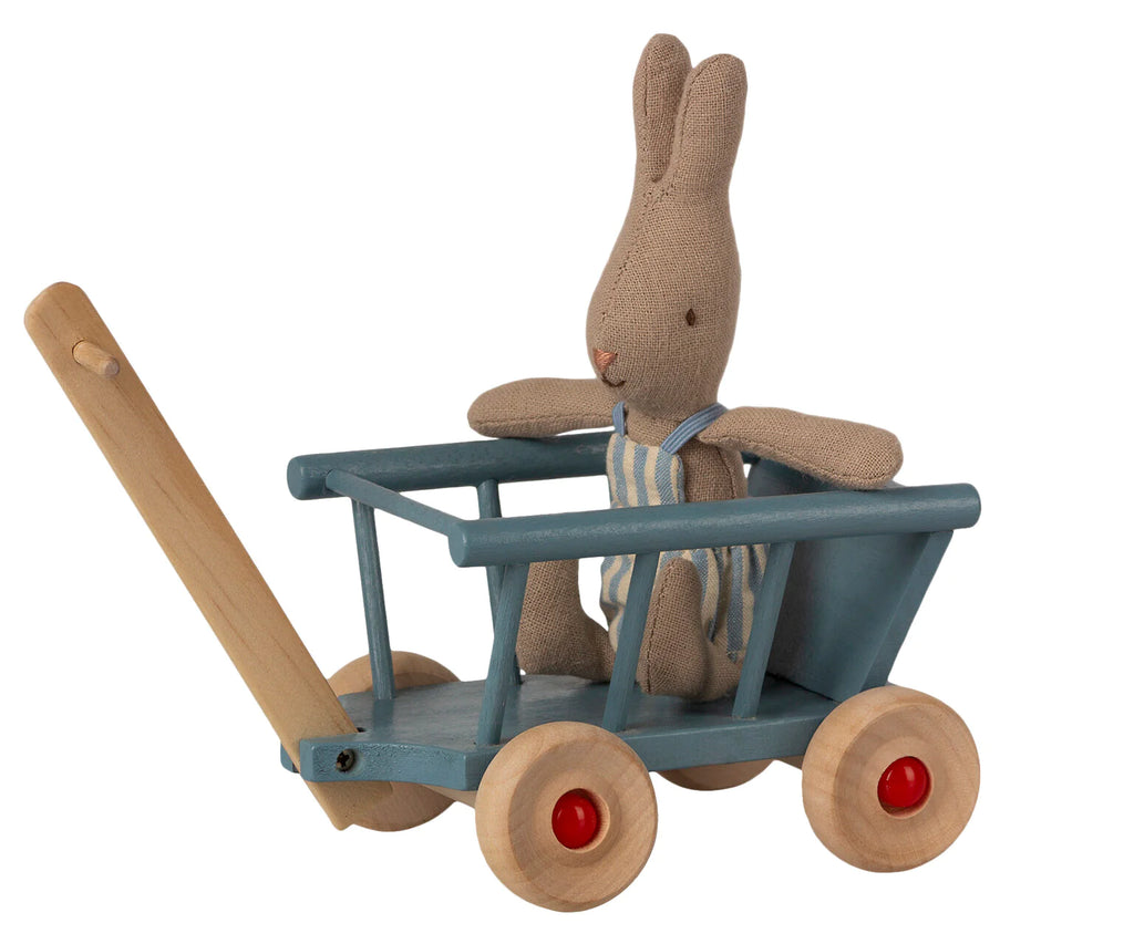 A stuffed toy rabbit with a linen texture, seated in a Maileg Wagon with red wheels, isolated on a white background.