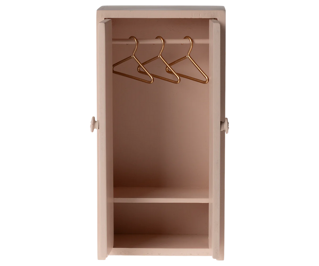 The Maileg Nursery Set offers a small light pink wardrobe for mouse families, with two compartments. The upper section includes three gold wire hangers, while the lower is empty. It features round handles on each side, making it an ideal addition to dollhouses for any Maileg fan.
