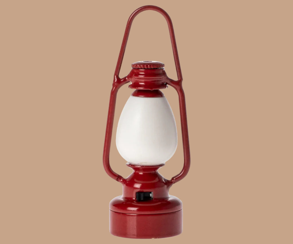 A red vintage-style lantern with a white frosted glass center, echoing the charming look of Maileg Little Sister Bedtime Set accessories, shown against a plain beige background.