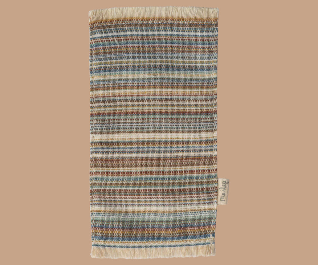 A rectangular Maileg Lounge Set rug with horizontal stripes in blue, brown, cream, and tan, fringed edges, and a small fabric tag—perfect for your Maileg Mouse home.