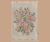 The Maileg Nursery Set includes a rectangular woven mat with fringed edges, decorated in a colorful floral pattern on a cream background and finished with a small fabric tag on the lower right edge. Ideal for placing under decor pieces.