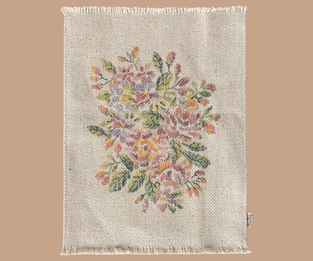 A beige woven fabric with fringed edges and central floral embroidery in pink, purple, yellow, and green—perfect for accessorizing the Maileg Little Sister Bedtime Set or adding charm to Mouse Furniture.