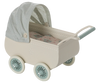 The Maileg Pram With Baby Mouse – Mint has a vintage style with a cream body, four mint green wheels, a matching handle, and a blue gingham canopy. Inside is a patterned mattress, adding extra charm to this adorable toy.