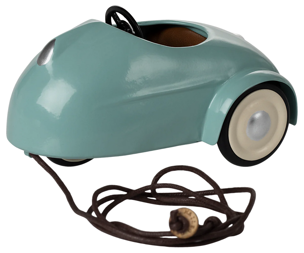 The Maileg Mouse Car in light blue is a small metal car with cream-colored wheels, featuring a pull string with a wooden handle and an open top showing the steering wheel, perfect for transporting mice on imaginative adventures. Ships in one week.