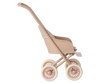 A Maileg Stroller, Micro - Powder in tan and beige plastic with four wheels, shown from the side against a softly blurred pastel-striped background.
