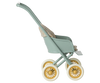 Side view of the Maileg Stroller, Micro - Mint featuring a vintage design with a green frame, yellow wheels, and a patterned seat. The empty stroller is set against a light striped background.