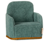 The Maileg Living Room Set includes a small, plush soft chair in green with a high back and armrests, featuring textured fabric and gold trim along the bottom edge—ideal for cozy evenings by a Maileg Fireplace.
