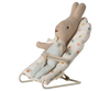A Maileg My Babysitter - Multi Dots holds a stuffed bunny dressed in blue overalls and a lace collar, secured in its white chair with colorful polka dots and a sturdy metal base.